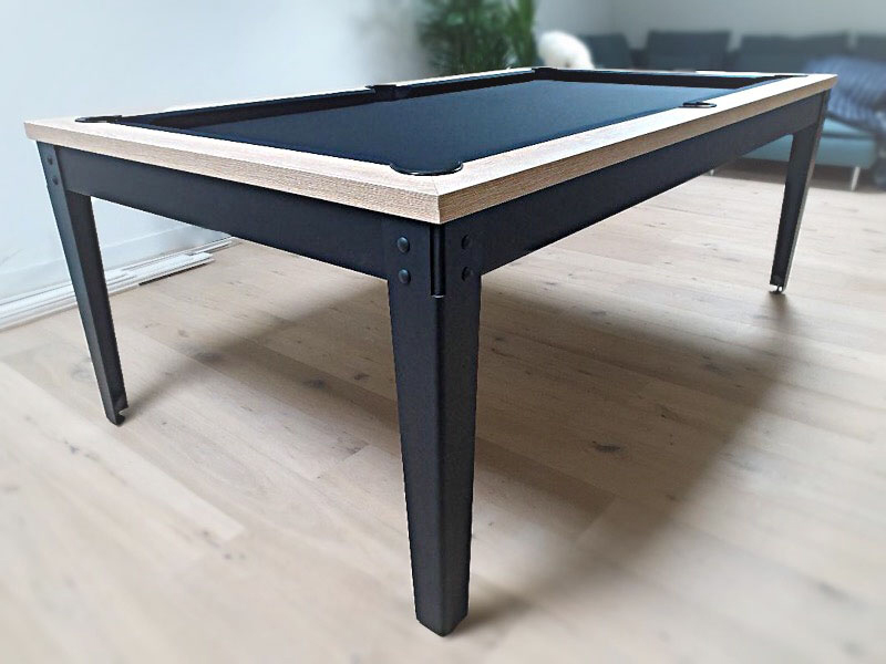 Billard Factory au design bicolore du piétement en acier noir qui se fond dans la couleur des plinthes noires couronnés du cadre en chêne naturel qui entoure le tissu noir